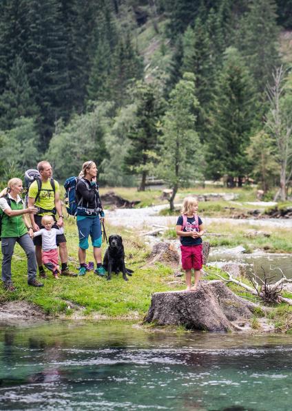 A national park ranger and a family are standing by a lake.